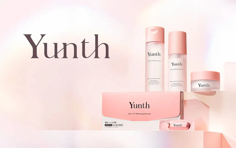 ピンク色の化粧品がいくつか並べられた画像です。化粧品には「Yunth」のロゴが入っており、「Pure VC Whitening Serum」や「Pure VC White Emulsion」などの商品名が記載されています。