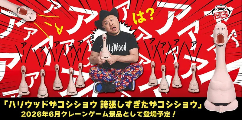 ハリウッドザコシショウのグッズのクレーンゲーム景品化を告知する画像。ザコシショウ本人が登場し、誇張された顔のグッズを持っている。背景には「ア」の文字が多数配置されている。