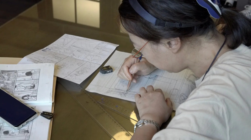 女性が机に向かって原画を描く様子