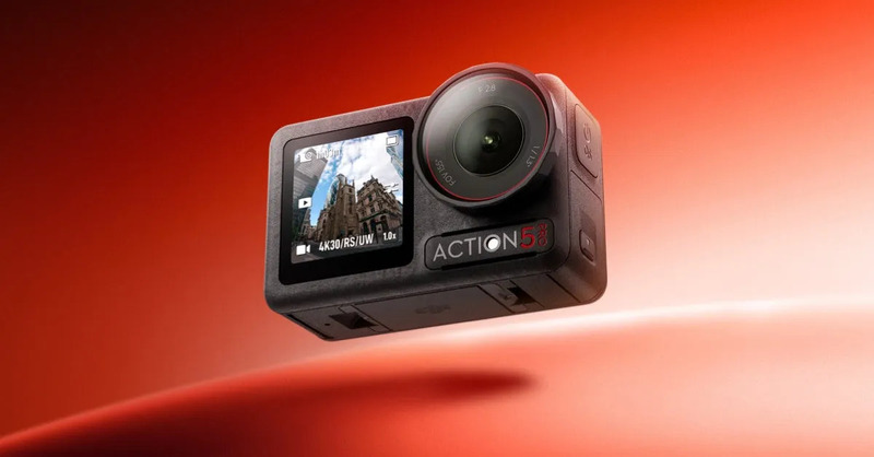 アクションカメラのクローズアップ画像。カメラは黒色で、レンズとディスプレイを備えています。背景は赤色。