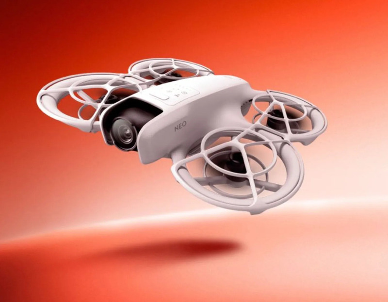 白いドローンが、オレンジ色の背景に浮かんでいる様子。NEO