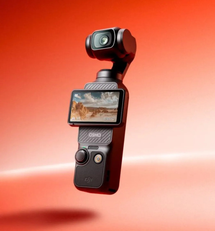 DJI Osmo Pocketカメラのクローズアップ写真。カメラは黒色で、画面に風景が表示されています。背景は赤色。