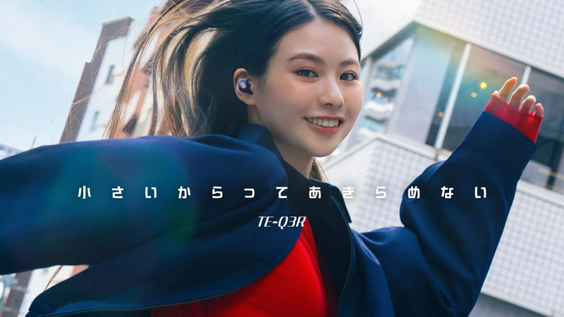 女性がイヤホンを付けている広告画像。女性は笑顔で、屋外にいる様子が写っています。