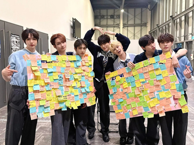 ステージで、観客席を前に、ファンからのメッセージが書かれたボードを見せるEPEXメンバー。