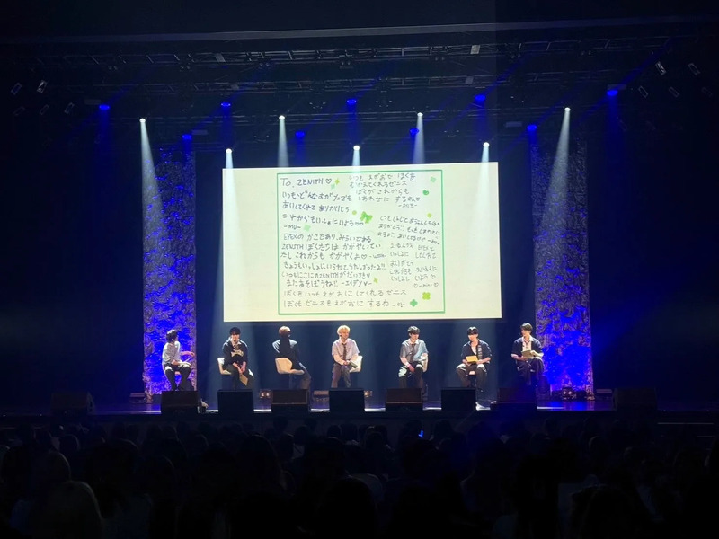 ステージ上で観客を前に、ファンからのメッセージボードを持って座るEPEXのメンバー。