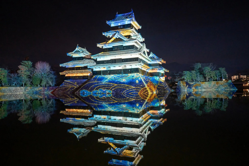 夜の松本城のライトアップ、水面反射