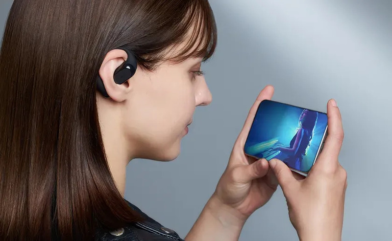 女性がイヤホンを装着し、スマートフォンで動画を見ている様子