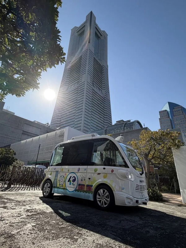 高層ビルを背景に走る自動運転EVバス