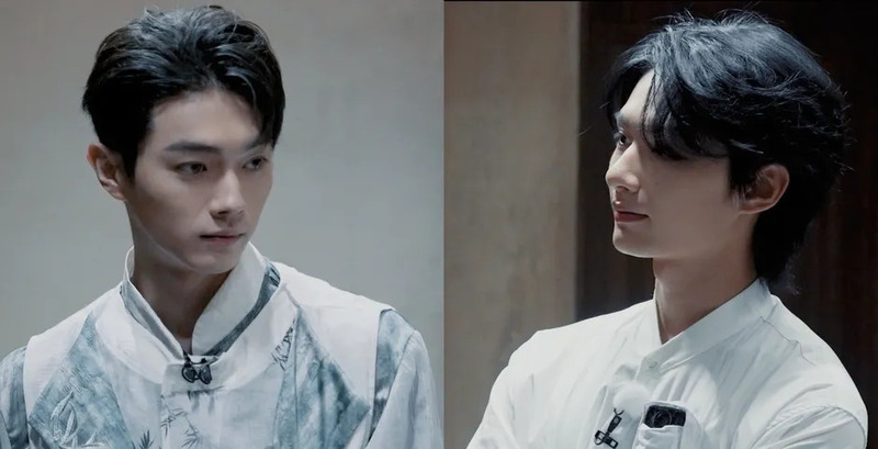 伝統的な要素を取り入れた衣装を着用した二人の若い男性が写っています。左の男性は柄物の服、右の男性は白いシャツを着ており、共にマイクを装着しています。インタビューや撮影の場面を捉えたもので、落ち着いた雰囲気です。