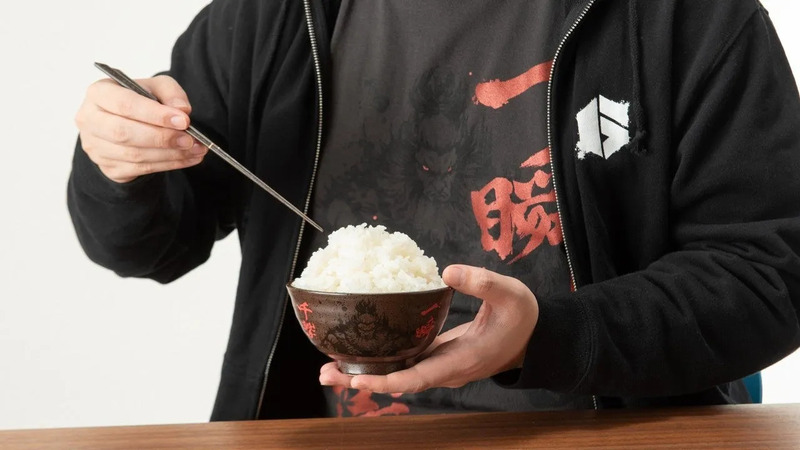 白いご飯が入ったお茶碗を、箸でつまもうとしている男性の画像です。