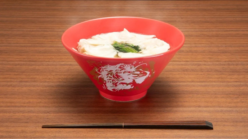 赤い丼に入った麺料理。箸が添えられている。