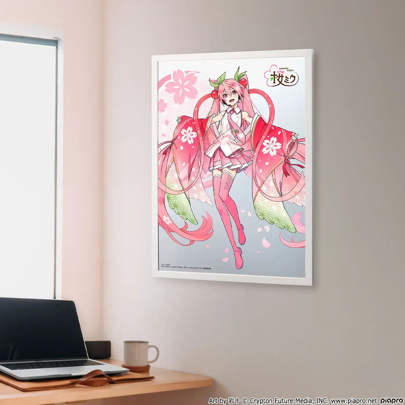 桜をテーマにしたイラストが飾られた部屋の写真。イラストには、ピンク色の髪と衣装を身に着けたキャラクターが描かれており、背景には桜の花びらが散っている。机の上にはノートパソコン、マグカップ、コースターが置かれている。