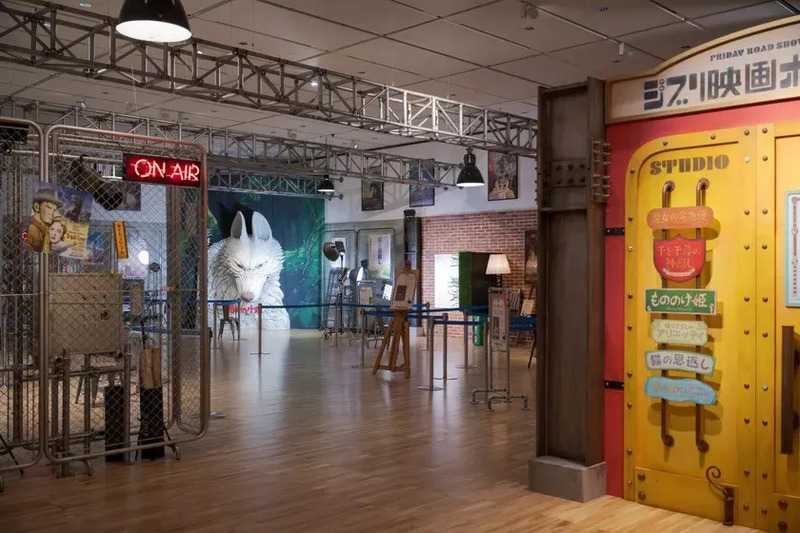 ジブリ映画の展示会場の様子。会場内には、スタジオの入口や、映画のキャラクターのオブジェ、展示物、ポスターなどが配置されている。