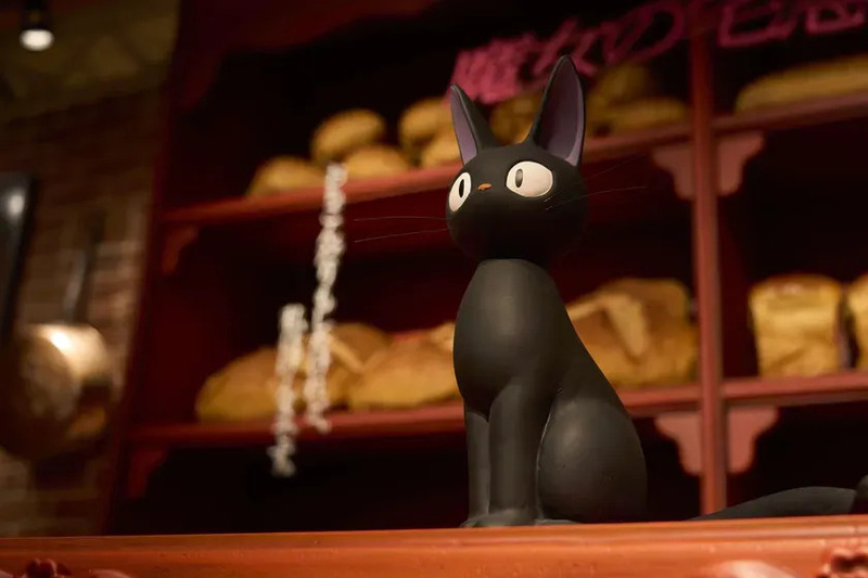 黒猫の置物と、パンが並んだ棚が印象的な写真。