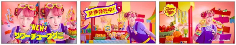 チュッパチャップスのCM。ピンクの髪の女性が、サワーチューブグミやチュッパチャップスなどの商品を持っている。背景にはお菓子屋さんやフルーツが並んでいる。