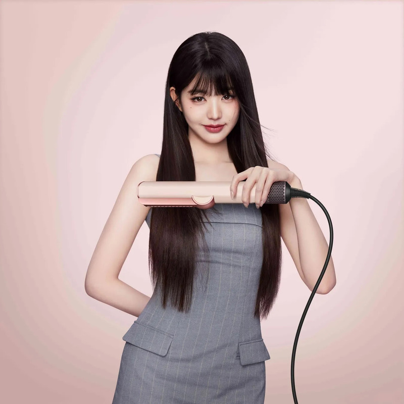 女性がヘアアイロンを持って微笑んでいる様子