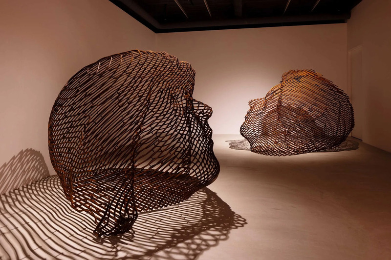 白い壁の前に置かれた2つの織り込まれた彫刻の芸術的な写真。