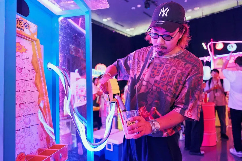 男性がゲーム機のようなものから飲み物を注いでいる様子