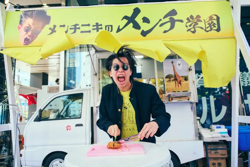 屋台でメンチカツを切る男性