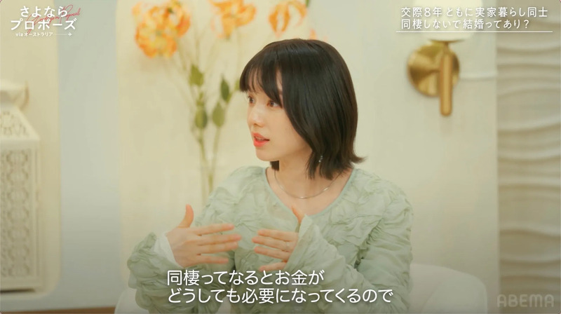 女性がインタビューを受けている様子。背景には花が飾られており、番組のロゴとテキストが表示されている。
