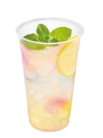 透明なプラスチックカップに入った、レモンとミントを添えた爽やかな飲み物。ピンク色と黄色のグラデーションが美しい。