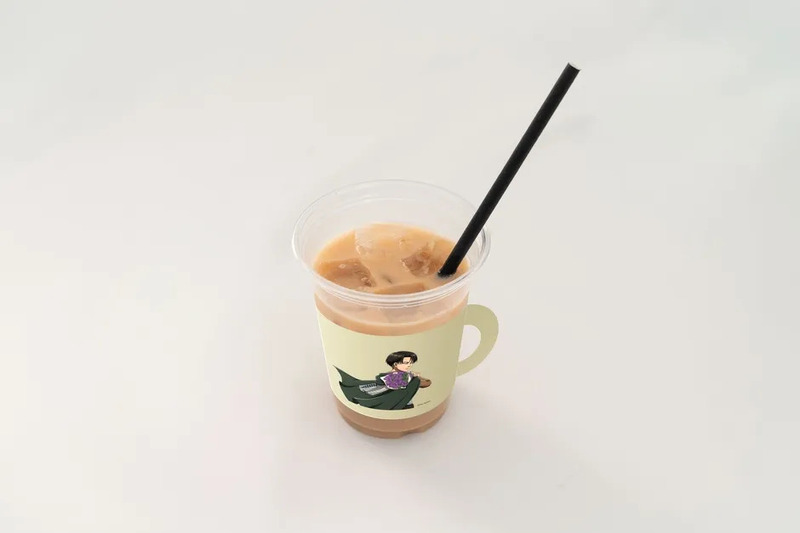 透明なプラスチックカップに入ったアイスコーヒー。カップにはキャラクターのイラストが描かれたスリーブが巻かれており、黒いストローが刺さっている。
