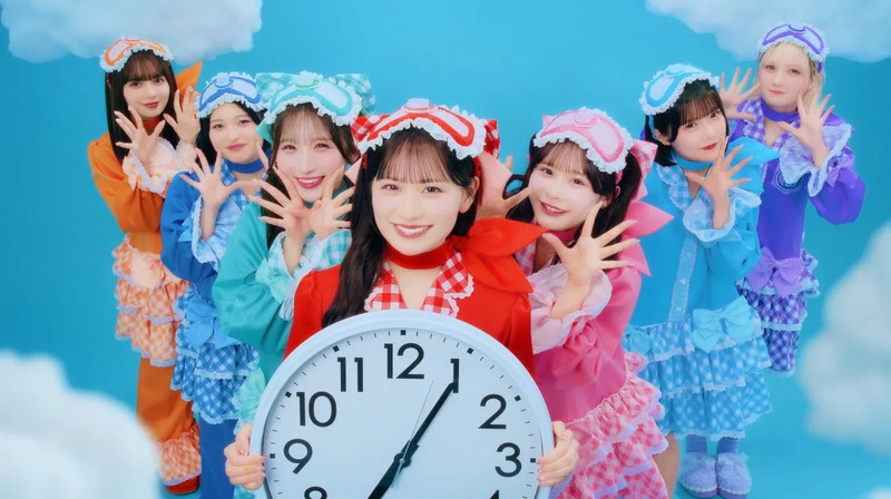 パジャマを着たアイドルグループの集合写真。メンバーは時計を持ち、笑顔でポーズをとっている。