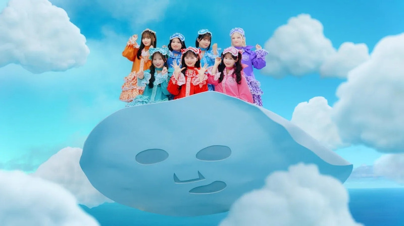 空に浮かぶパックの上に乗ったアイドルグループの集合写真。