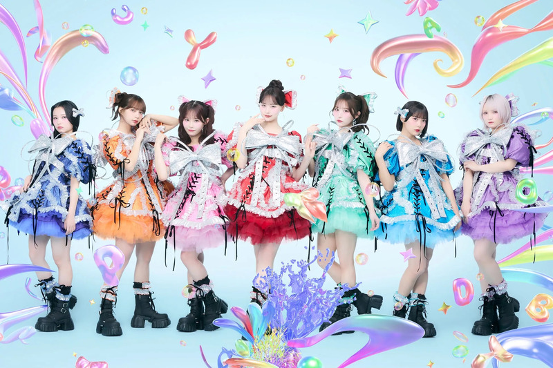 7人の女性アイドルグループが、カラフルな衣装を着てポーズをとっている写真。